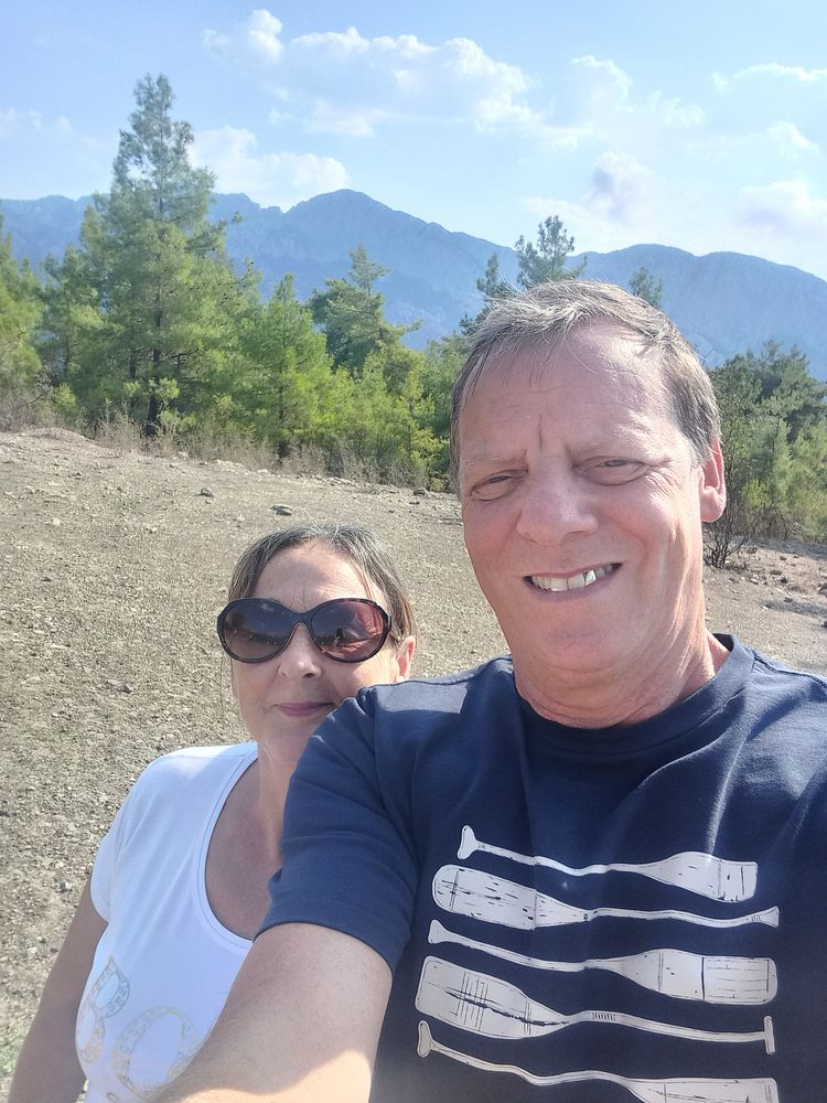 Paul and Tracey Chambers selfie outdoors with trees and mountains behind