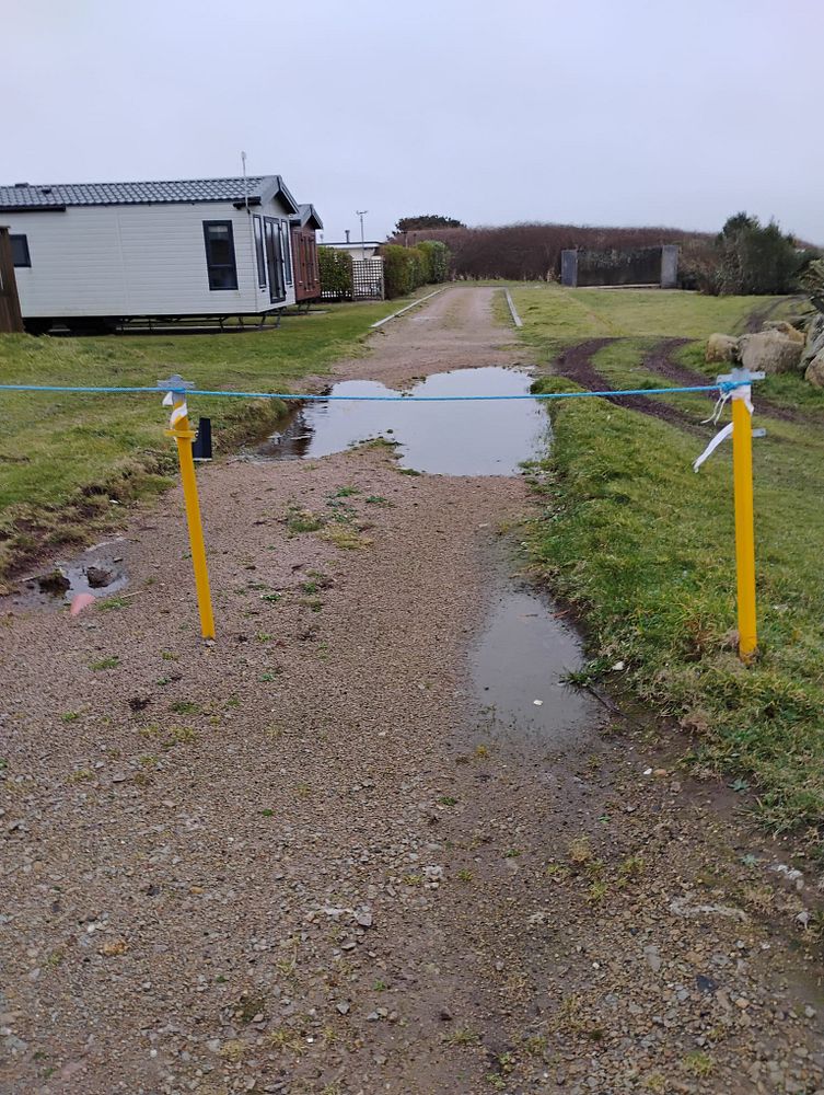 Flooded gravel track at Seaview Holiday Park beside static caravans