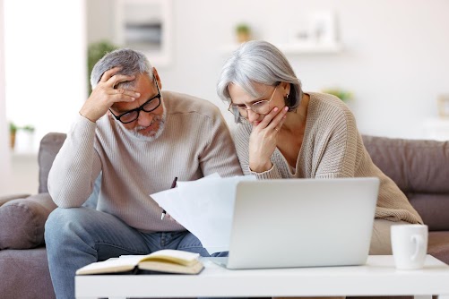 Worried older couple reviewing bills and laptop, discussing ongoing holiday park fees